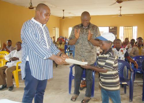 Master Chijioke Samuel Ukachu, a 10 year old primary six pupil being presented with a letter of commendation for profitably overseeing the sale of water from the water facility donated by the Adure and Onyima Obioha Foundation at his spare time.